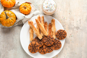 Plate with Halloween cookies, glass of cocoa and pumpkins on grunge background