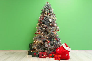 Santa bag with presents and Christmas tree near green wall