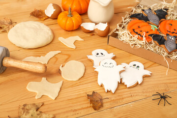 Pieces of raw dough and Halloween cookies on wooden background