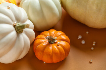 Halloween pumpkins with pearls on beige background, closeup