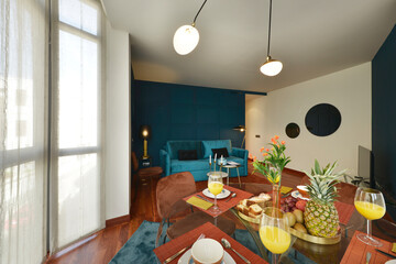 Nice beveled edge clear glass circular dining table with tableware with fresh fruits and sweet desserts