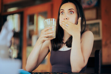 Woman Reacting after Drinking a Sour Beverage. Unhappy girl drinking a citrus beverage with a bad taste
 - obrazy, fototapety, plakaty