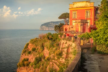 Muurstickers Sorrento cityscape above cliffs at golden sunset, Gulf of Naples, Southern Italy © Aide