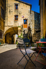 Obraz premium table and chair in a narrow street of the medieval village of Saint Montan in the south of France (Ardeche)