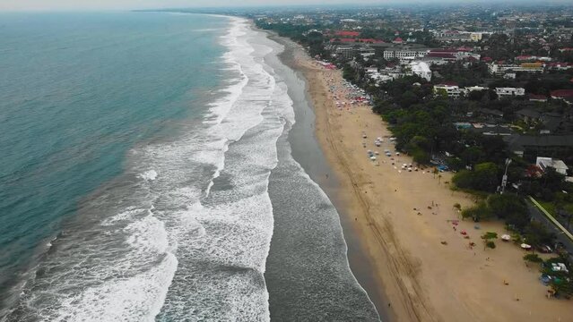 Beautiful Seminyak and Double Six Beach drone footage in Bali with cinematic waves many crowded people enjoying sunset after Covid-19 pandemic. This footage was shot during Sunset time in 1080p.