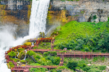 Tourists in raincoats on the Cave of the Winds Lookout, stairs and platforms, wooden walkways, ponchos for an up-close and wet view of the Bridal Veil Falls at the foot of the Niagara Falls, on Goat