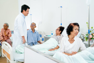 Obraz premium Asian doctor meet and talk with senior patient in common patient room and they look happiness during diagnosis and treatment in hospital.
