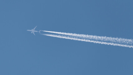 Avion comercial moderno volando a altitud de crucero dejando tras de si la estela blanca turbulenta