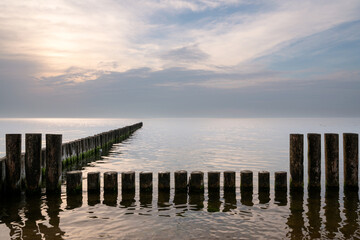 View of wooden breakwaters against the background of the sunset sky and calm on the Baltic Sea, Svetlogorsk, Kaliningrad region, Russia
