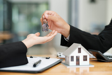 Real estate agent giving house keys to client after signing contract.