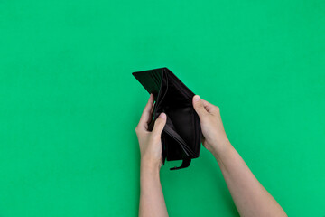 Woman hand open an empty wallet on green background