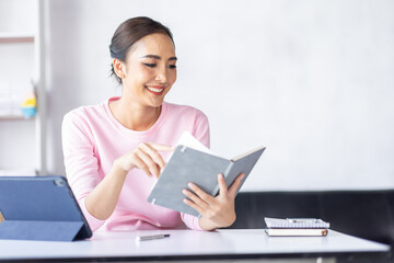 Young business Asian woman working in note and tablet the home workplace, reading and taking notes on the paper, accounting, tax, Financial, Business concept