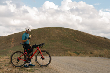 Fototapeta premium Cyclists practicing on gravel roads. he is eating a banana