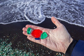Selective focus. Colored glasses on the hand. Glass beach.