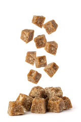jaggery pieces falling on white background, golden brown colored cube shaped unrefined sugar...