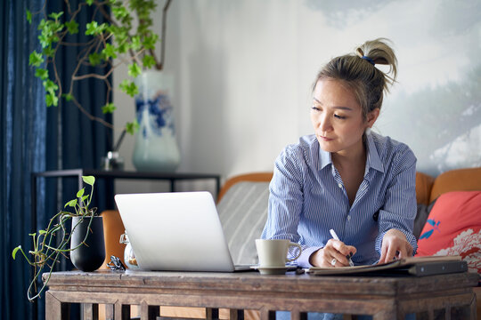 mature asian woman working from home using notebook computer