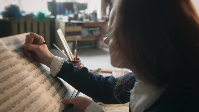 Lady musician reads sheet music book and makes notes