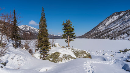 A path trampled through snowdrifts leads to a frozen lake covered with pure untouched snow....
