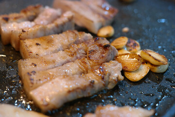 Grilling pork belly on an iron plate