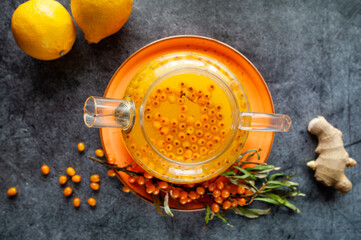 Sea buckthorn tea, top view. Still life kettle, berries and lemons. Orange sea buckthorn drink, juice. Autumn mood.