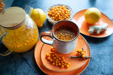 Sea buckthorn tea. Still life cup with tea, berries and lemons. Orange sea buckthorn drink, juice. Autumn mood.