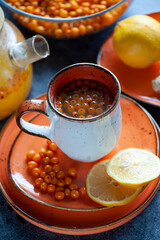 Sea buckthorn tea. Still life cup with tea, berries and lemons. Orange sea buckthorn drink, juice. Autumn mood.