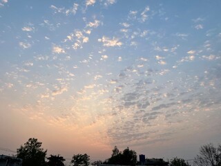 Obraz premium Sunset sky with yellow and orange tint and small clouds