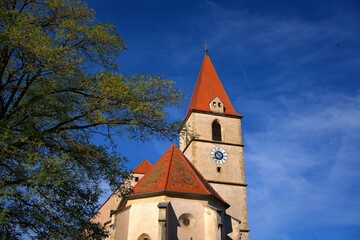 kirchturm in semriach vor blauem himmel mit baum