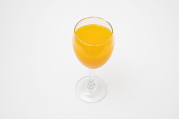 Orange juice in wine glass on white background