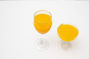 Orange juice in wine glass on white background