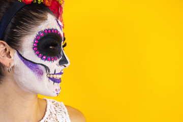 portrait of Mexican Catrina, young hispanic woman on yellow copy space for Halloween or day of the Dead party in Mexico in Latin America