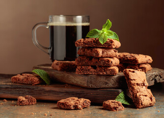Pieces of fresh brownie with mint and a cup of black coffee.