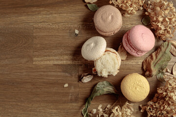 Macaroons with dried flowers on a wooden table.