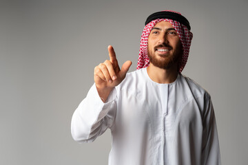 Young Arab man pointing hand to copy space on gray background