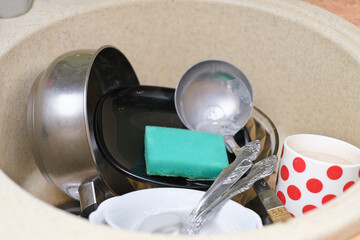 dirty dishes and kitchen utensils in a sink. messy kitchen. cluttered sink. daily routine, chores and housekeeping. close up