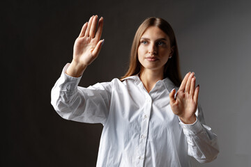 Young female entrepreneur touching virtual screen against grey studio background