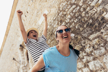 Mother and son enjoying piggyback ride during sightseeing of the old town