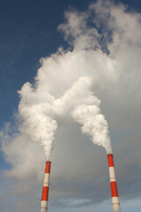 Huge puffs of smoke from chimneys in winter. Harmful emissions from smokestacks of a thermal power plant. Environment and ecology crisis. Bottom up view.