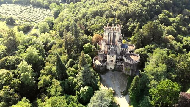 Butron Castle surrounded by lush forest under scenic sunlight in Gatika, Basque Country. Aerial 4K