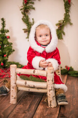 
Little cute boy dressed as Santa Claus in a room decorated for Christmas. Christmas and children