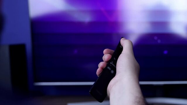 Closeup of a hand turning on a TV with a remote controller