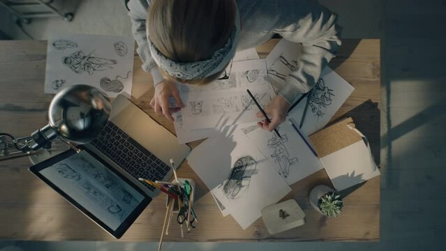 Young woman working on a storyboard in a design studio. A laptop and stationary jar on the table. Woman drawing sketches as a roadmap for the video.