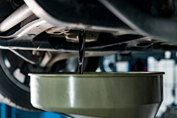 Old dirty oil pouring from the car engine in car service station close up