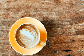 Top view of a latte art coffee on old wooden table.