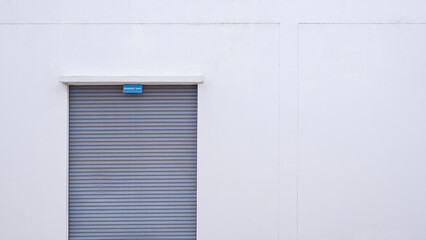 Obraz na płótnie Canvas Roller shutter door of generator room on white concrete wall, front view with copy space
