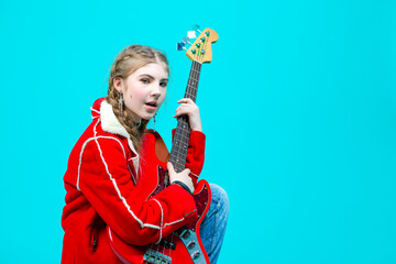 Musical Ideas. Winsome Caucasian Guitar Player With Yellow Bass Guitar Posing In Fashionable Red Jacket Over Trendy Turquoise Background.