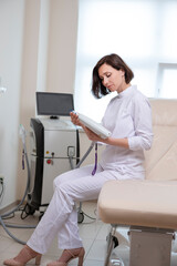 Females In Business. Professional Confident Female Doctor Posing in Doctor's Smock And Holding Intence Pulse Light Apparatus in Laser Rejuvelation and Beauty Treatment Salon.