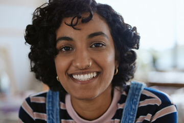 Face, portrait and happy with a young woman feeling carefree or cheerful with a smile closeup....