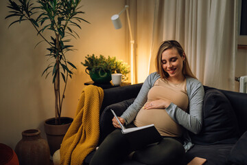 european pregnant woman sit in her living room and reading book