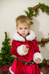 Little cute boy dressed as Santa Claus in a room decorated for Christmas. Christmas and children